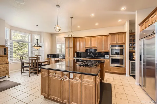 a kitchen with stainless steel appliances a stove a sink a oven a dining table and chairs