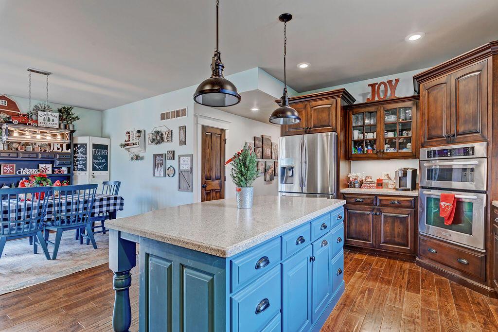 4045 Russell Road Mount Gilead, OH 43338 - Photo 15 of 74 • Handscraped hardwood flooring • Baby blue painted walls • Amish custom cabinets • New KitchenAid® stainless steel refrigerator ~ 2019 • New KitchenAid® stainless steel dishwasher ~ 2019 • KitchenAid® stainless steel convection oven/microwave oven bottom • Farmhouse sink • Pantry • Electric stovetop with hood • Large island with seating • Corian® countertops