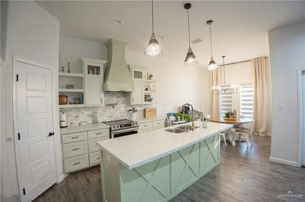 a kitchen with stainless steel appliances kitchen island granite countertop a sink a stove a dining table and chairs