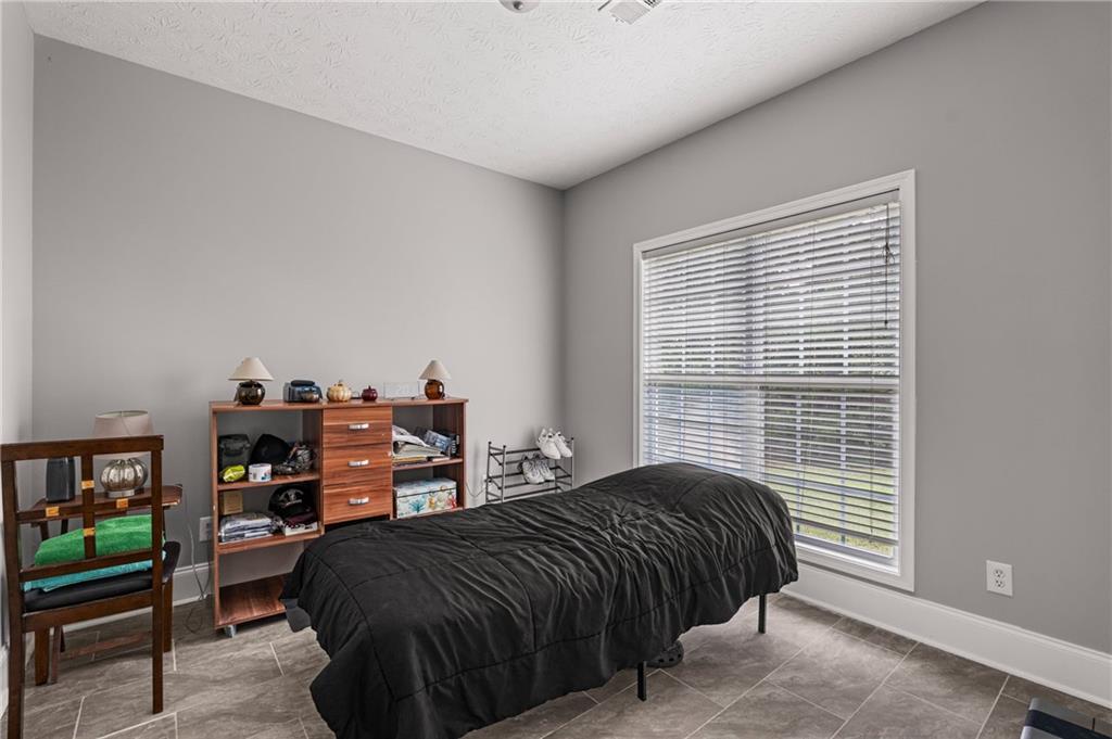 1449 Cummings Road Smiths Station, AL 36877 - Photo 7 of 28 Room featuring a window with blinds, light gray walls, white trim, and rectangular tile flooring