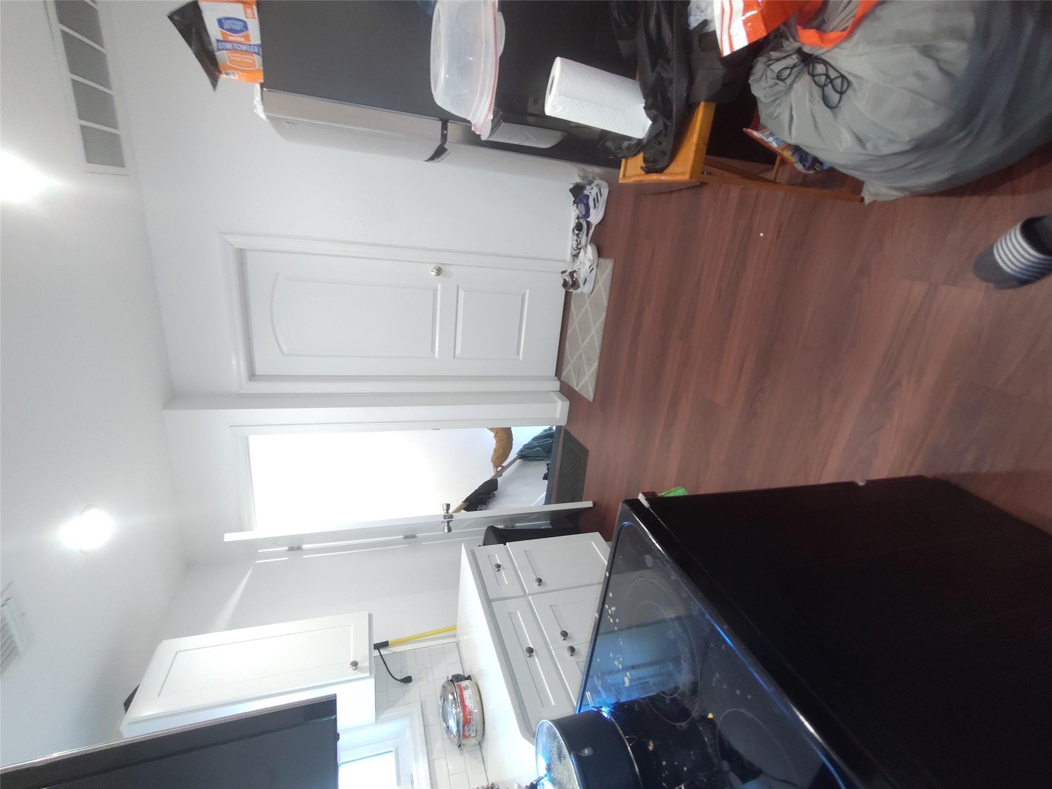 2167 A Great Neck Road Copiague, NY 11726 - Photo 15 of 18 Kitchen with stove, dark wood-type flooring, white cabinetry, tasteful backsplash, and fridge
