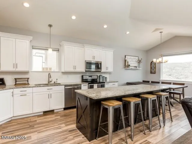 a kitchen with stainless steel appliances granite countertop a stove a sink a oven a dining table and chairs