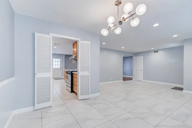 a view of an empty room with chandelier fan