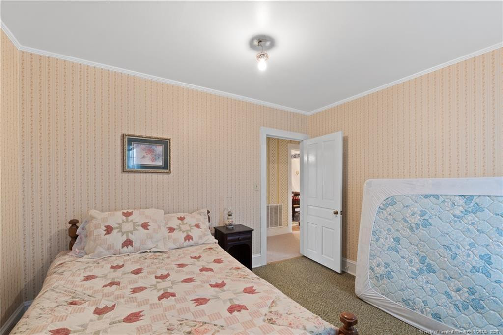 6131 Stewart Road Godwin, NC 28344 - Photo 22 of 27 a bedroom with a large bed and a chandelier