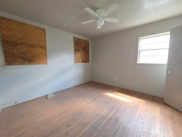 a view of an empty room with a window and wooden floor