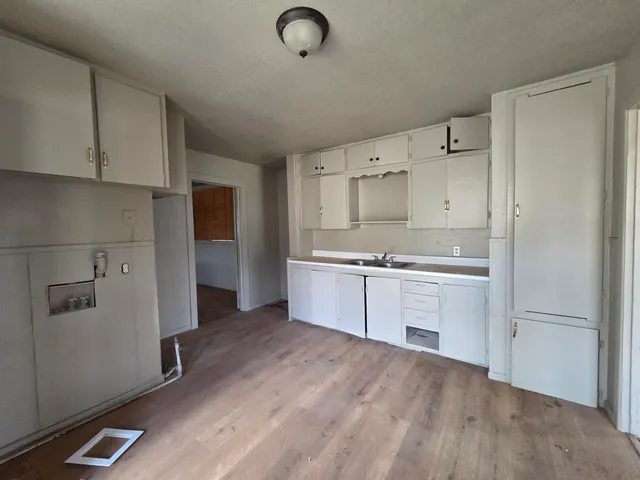 a kitchen with granite countertop a refrigerator a sink and white cabinets