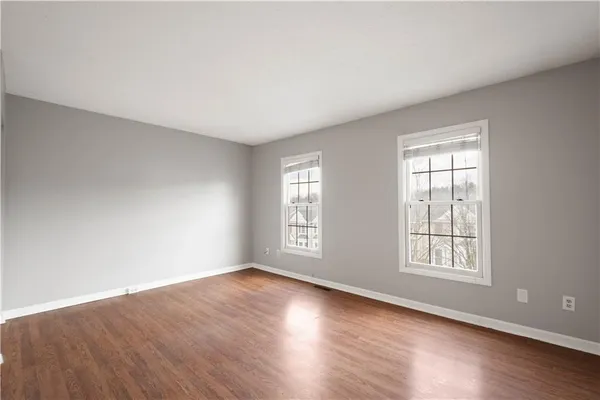 a view of an empty room with wooden floor and window