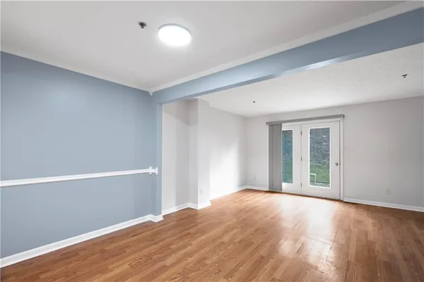 a view of an empty room with wooden floor and a window