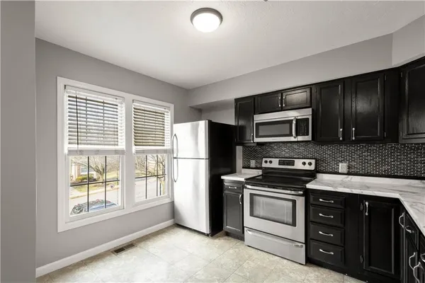 a kitchen with stainless steel appliances granite countertop a stove a sink and a refrigerator