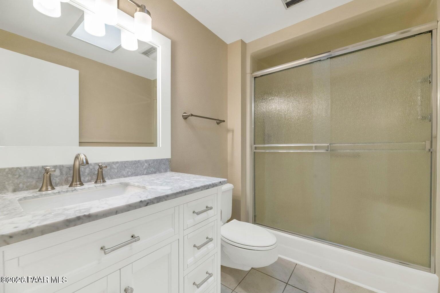 12602 West Rampart Drive Sun City, AZ 85375 - Photo 13 of 28 a bathroom with a granite countertop sink toilet and shower