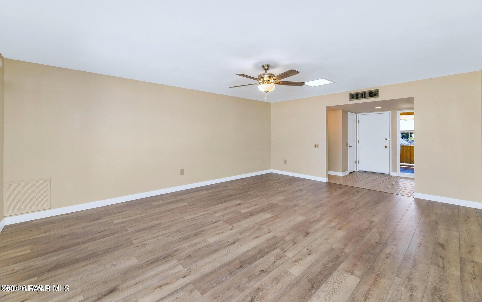 12602 West Rampart Drive Sun City, AZ 85375 - Photo 4 of 28 a view of an empty room with wooden floor and a ceiling fan