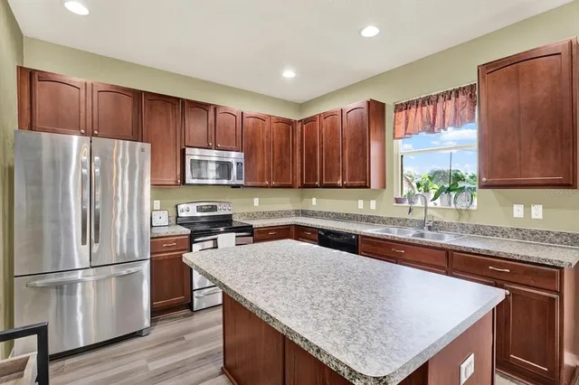 a kitchen with stainless steel appliances granite countertop a refrigerator a sink a stove a microwave and wooden cabinets