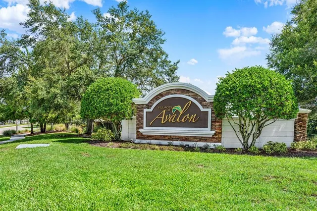 a view of a white house next to a yard with large trees
