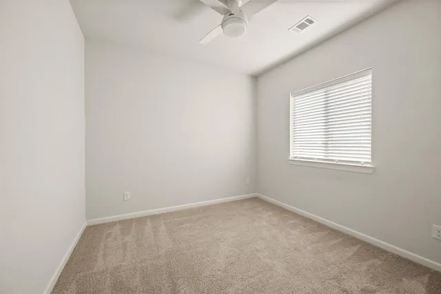 an empty room with a window and a fan
