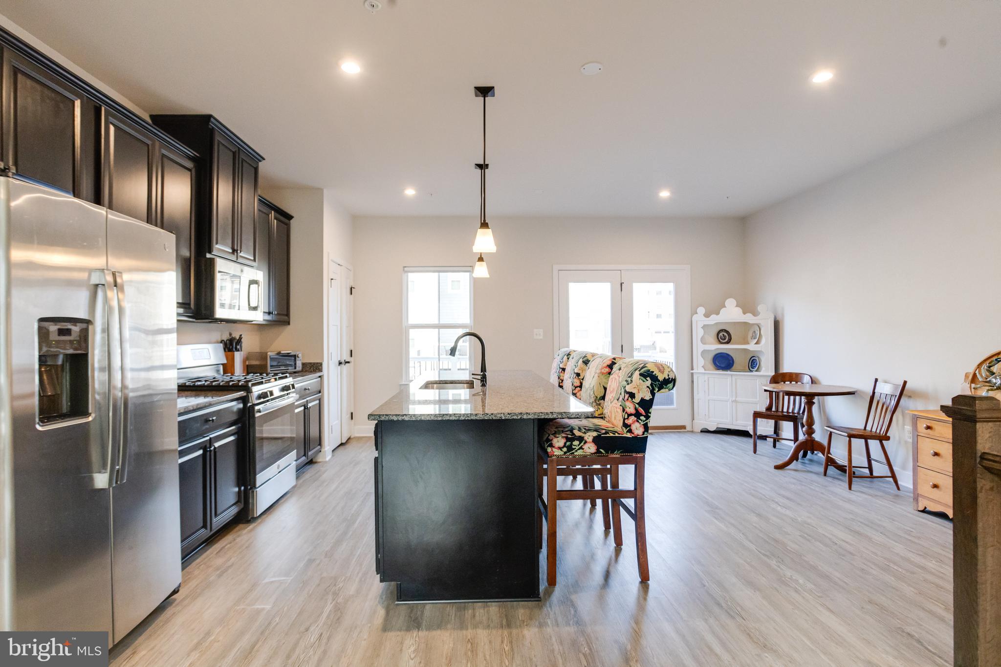 6222 Islington Street Middle River, MD 21220 - Photo 16 of 76 a kitchen with stainless steel appliances granite countertop a refrigerator a stove top oven a dining table and chairs with wooden floor