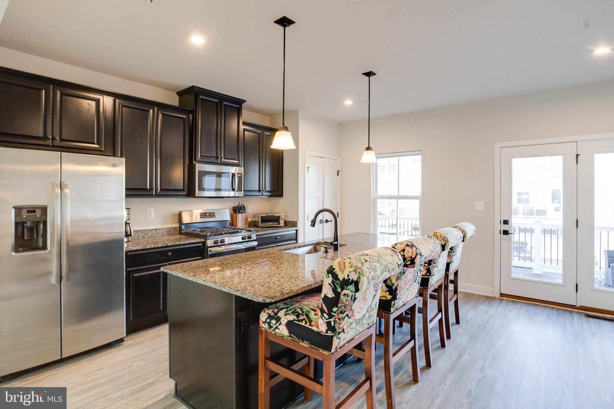 6222 Islington Street Middle River, MD 21220 - Photo 20 of 76 a kitchen with granite countertop a table chairs stainless steel appliances and wooden floor