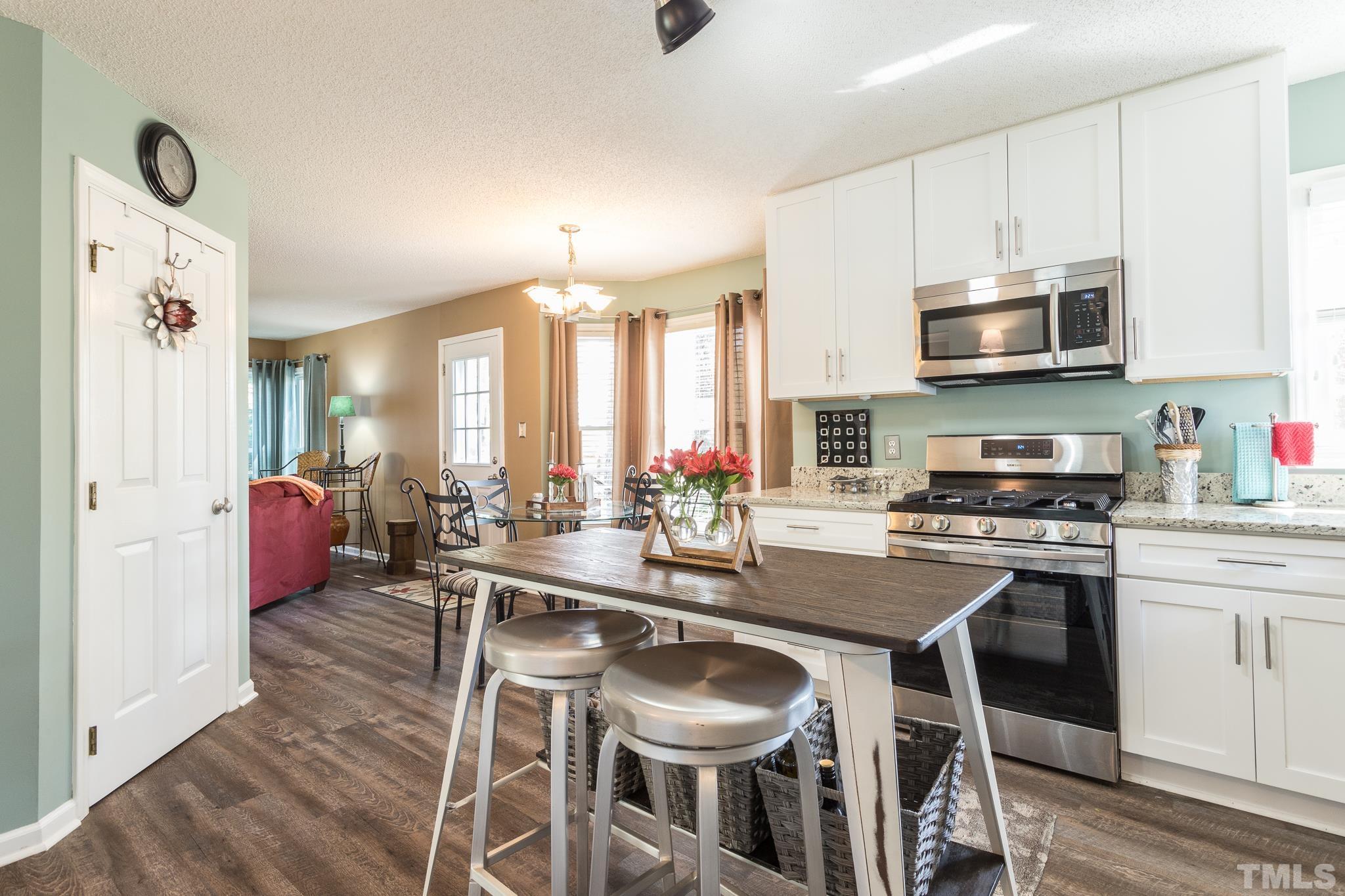 2352 Declaration Drive Raleigh, NC 27615 - Photo 12 of 28 a kitchen with stainless steel appliances granite countertop a stove top oven a sink a dining table and chairs with wooden floor