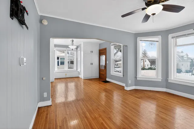 a view of an empty room with window and wooden floor