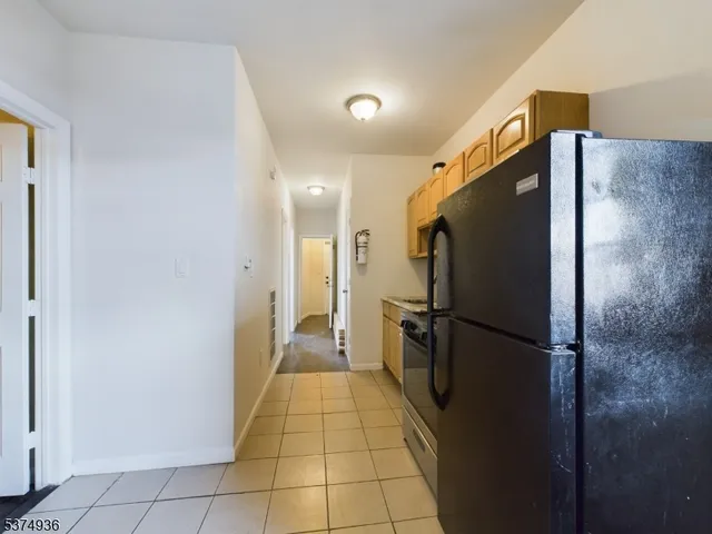 a view of a refrigerator in kitchen and an empty room
