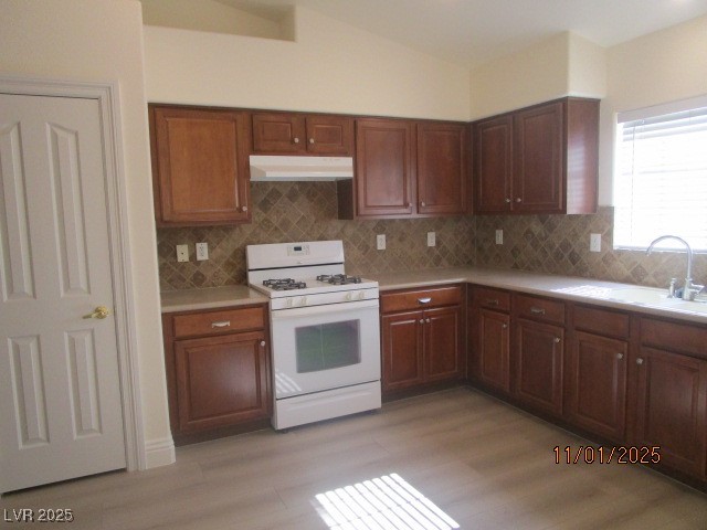 8661 Little Fox Street Las Vegas, NV 89123 - Photo 5 of 18 Kitchen featuring gas range gas stove, light countertops, decorative backsplash, under cabinet range hood, and light wood-style flooring