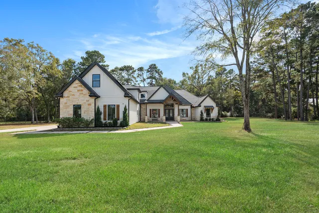 a view of a house with a big yard and large trees