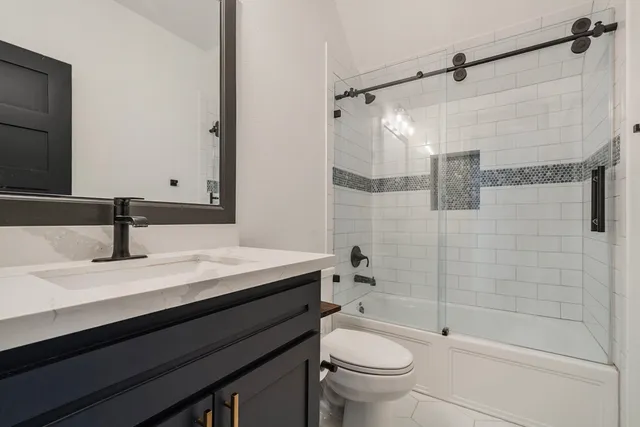 a bathroom with a granite countertop sink a toilet and shower