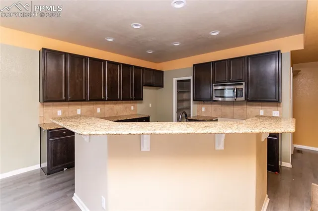 a kitchen with stainless steel appliances granite countertop a sink and a refrigerator