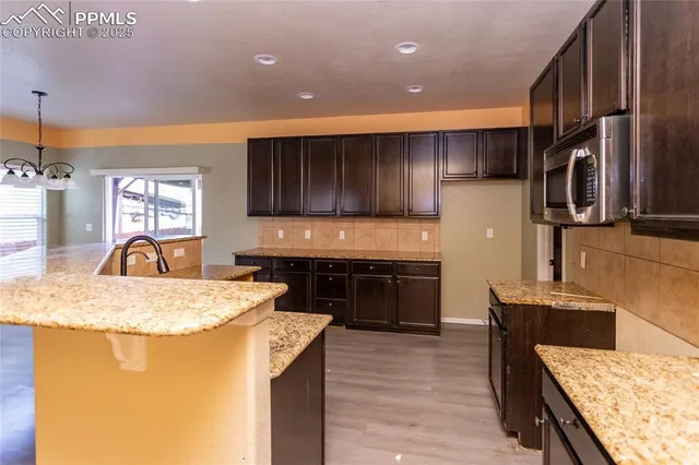 a kitchen with stainless steel appliances kitchen island granite countertop a sink refrigerator and cabinets