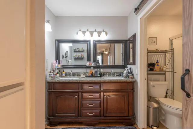 a bathroom with a granite countertop sink a toilet and a mirror