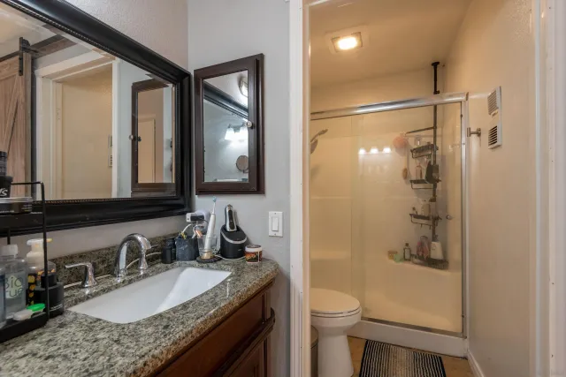 a bathroom with a granite countertop sink toilet mirror and shower