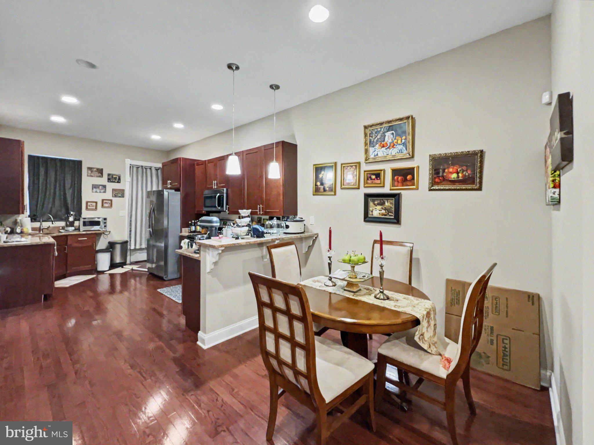1610 North Broadway Baltimore, MD 21213 - Photo 7 of 18 a dining room with kitchen island furniture a wooden floor and a view of kitchen