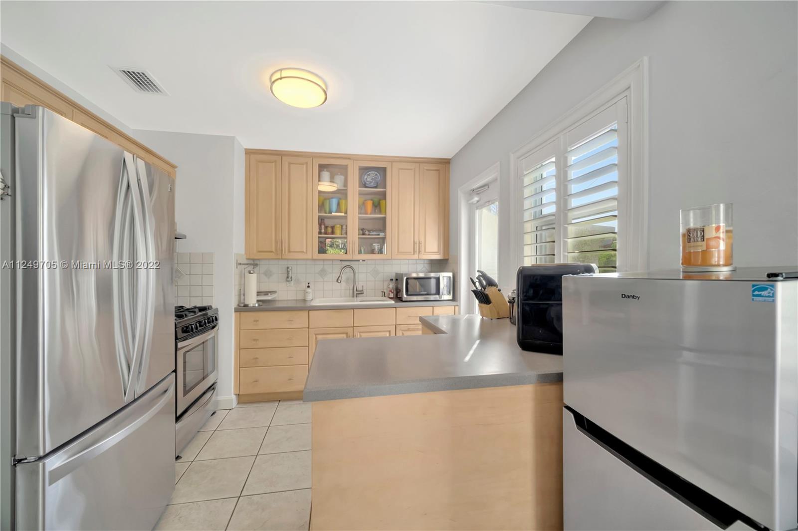 4290 Southwest 11th Street Miami, FL 33134 - Photo 10 of 20 a kitchen with stainless steel appliances granite countertop a refrigerator a stove and a sink with large window