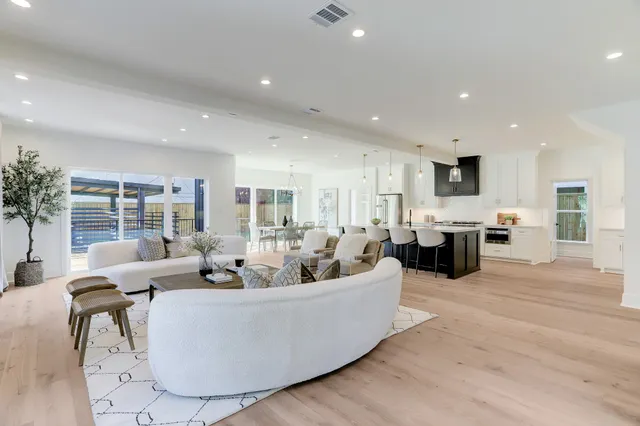 a living room with furniture kitchen view and a large window