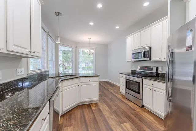 a kitchen with stainless steel appliances granite countertop a stove a sink and a refrigerator