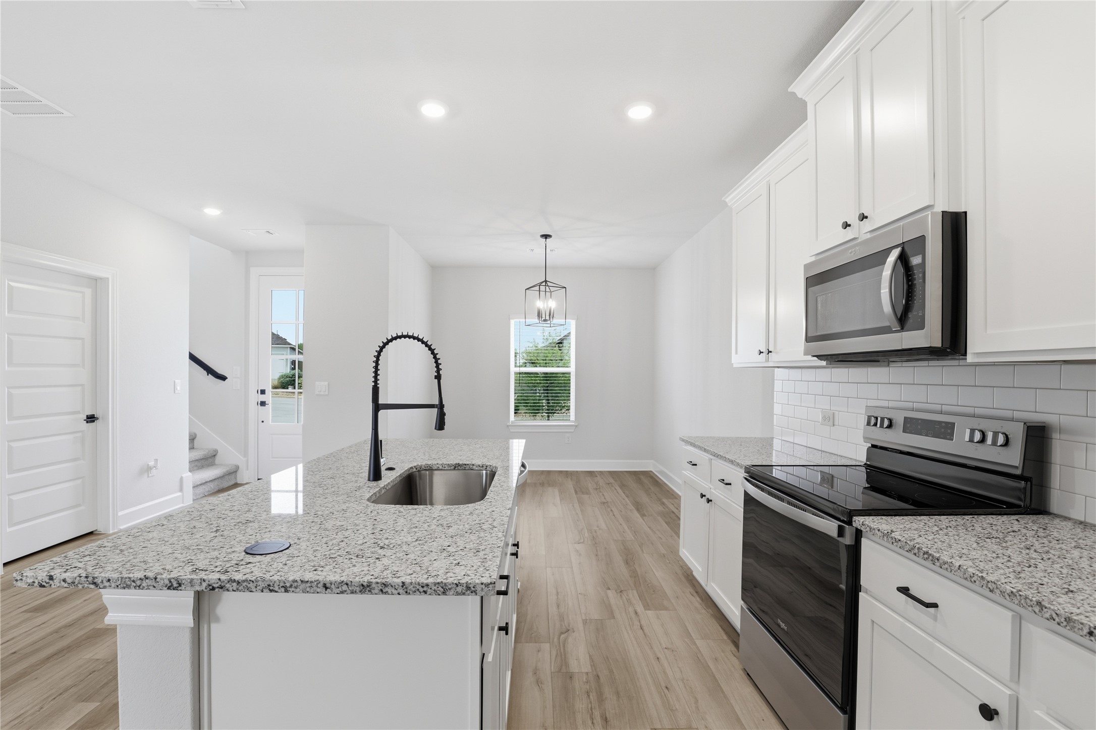 9320 Gladsome Path Manor, TX 78653 - Photo 23 of 34 a kitchen with stainless steel appliances granite countertop a sink and a stove top oven with wooden floor