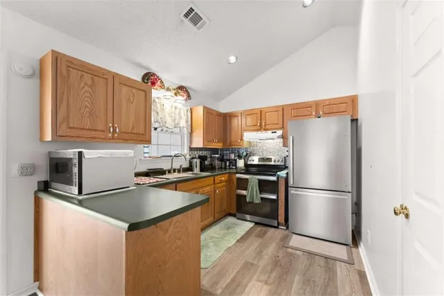 a kitchen with granite countertop stainless steel appliances a refrigerator a sink and cabinets
