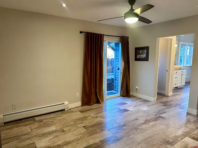 an empty room with wooden floor closet and windows