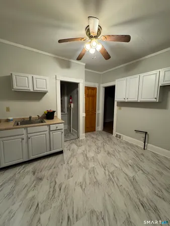a large white kitchen with kitchen island a sink stainless steel appliances and cabinets