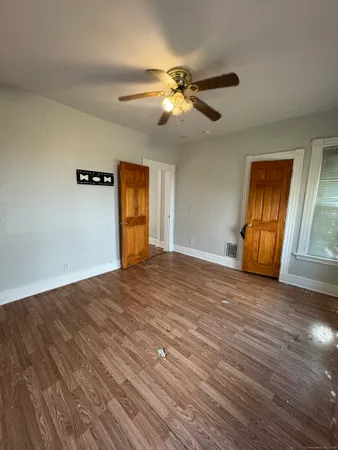 a view of empty room with wooden floor and fan