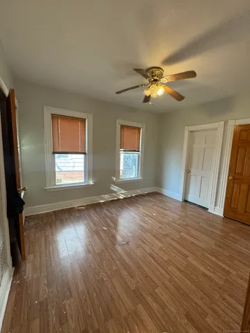 a view of empty room with wooden floor and fan