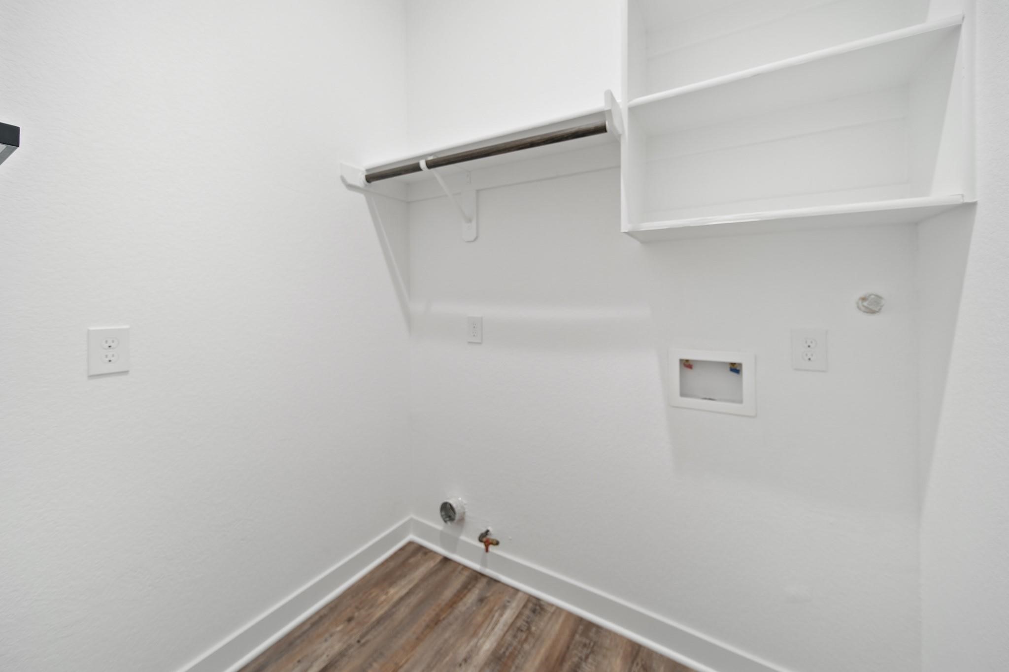 5813 England Street, Unit A Houston, TX 77021 - Photo 17 of 18 Compact laundry room with hookups, shelving, and a rod for hanging clothes, complemented by modern flooring.