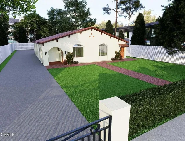 a view of a white house with a yard plants and large tree