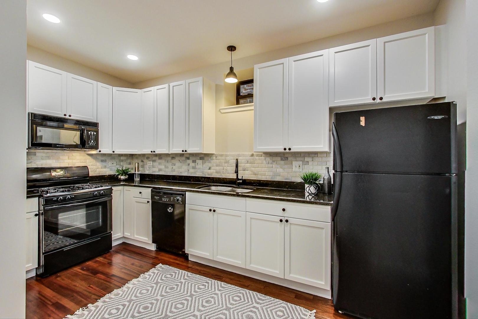 613 North Racine Avenue, Unit 1 Chicago, IL 60642 - Photo 6 of 21 a kitchen with granite countertop a refrigerator stove and microwave