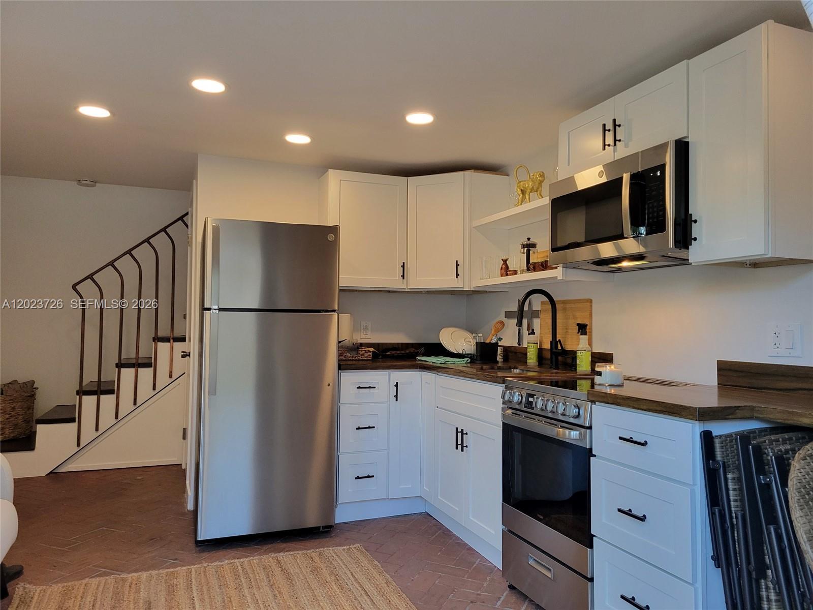 5866 Southwest 60th Street, Unit 3 Miami, FL 33143 - Photo 3 of 8 a kitchen with stainless steel appliances granite countertop a refrigerator a stove top oven a sink and dishwasher with wooden floor