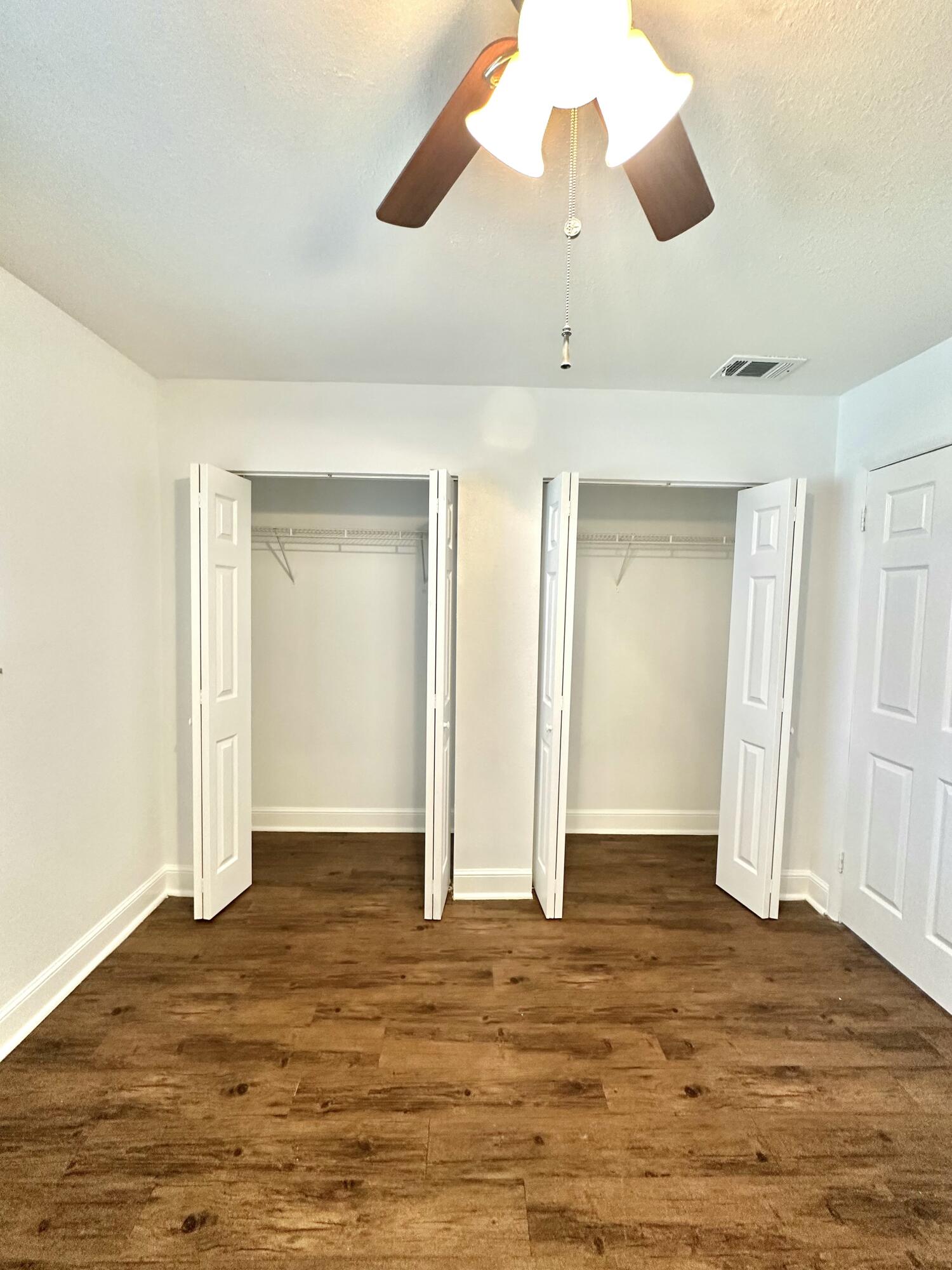 210 Tiffany Drive East, Unit 1 West Palm Beach, FL 33407 - Photo 6 of 10 an empty room with wooden floor and ceiling fan