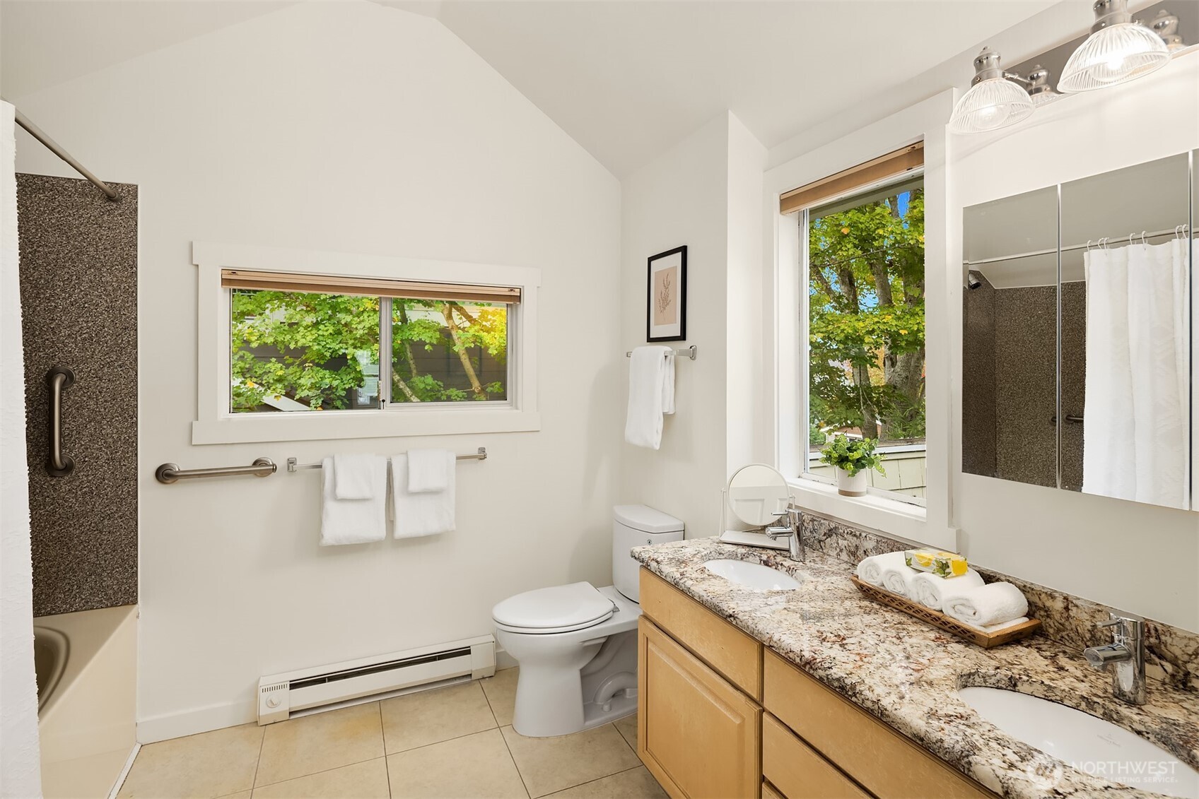 5722 Keystone Place North Seattle, WA 98103 - Photo 24 of 38 a bathroom with a granite countertop toilet a sink and a large mirror