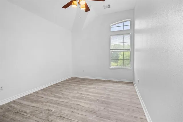 an empty room with windows and fan