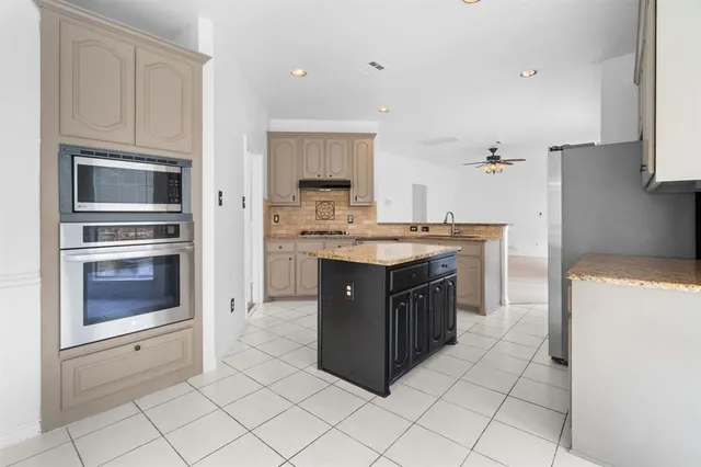 a kitchen with stainless steel appliances granite countertop a stove a sink and a refrigerator
