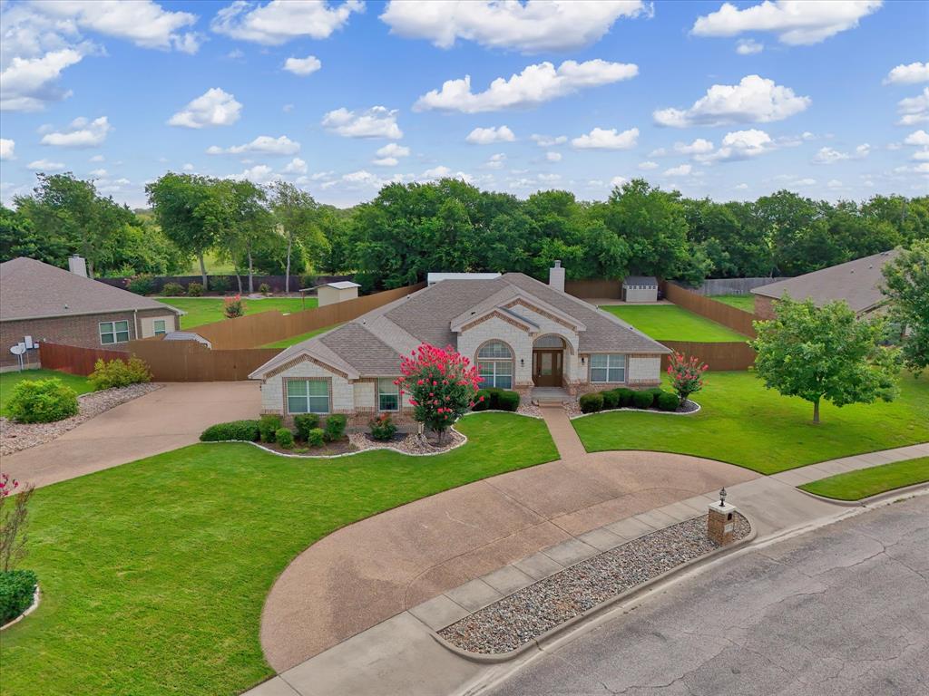 Single-story residence featuring a stone and siding exterior, front yard landscaping, and an expansive driveway