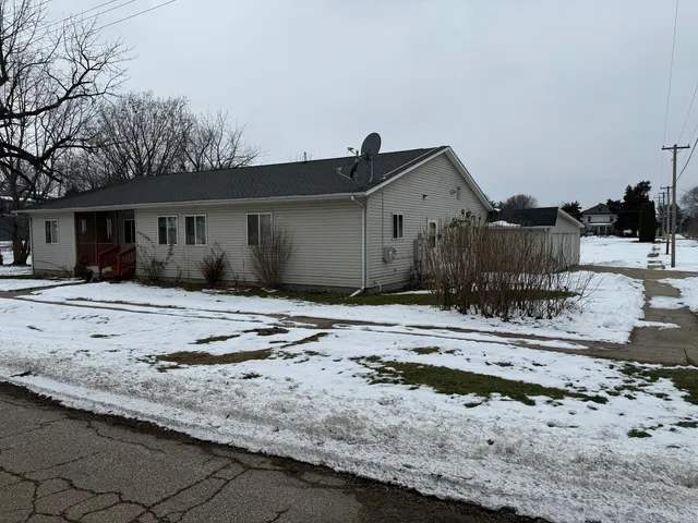 a view of a dry yard covered with snow in front of it